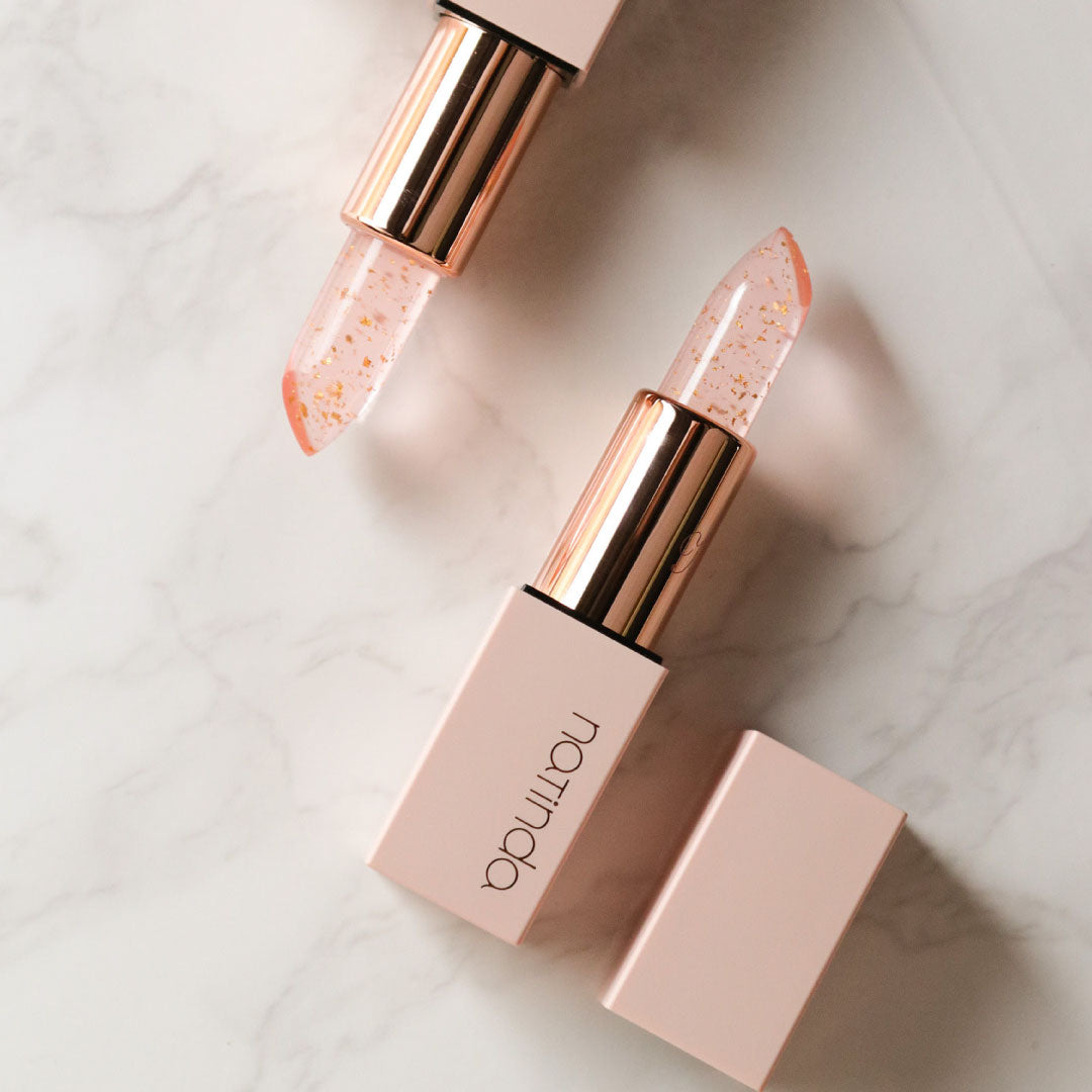 Lipstick with rose gold casing on a light marble background