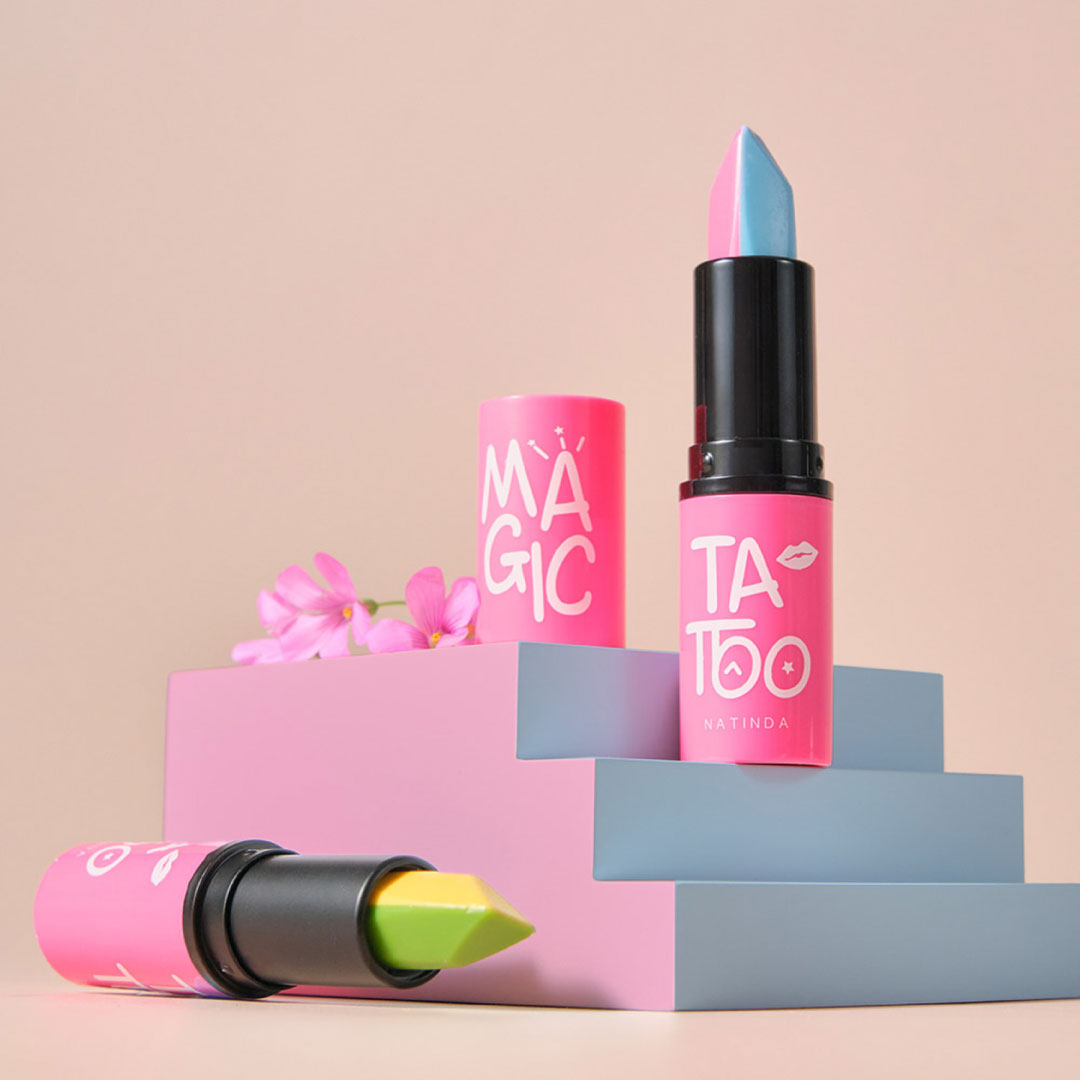 Colorful lipsticks with 'TA TOO' branding on a pink and blue geometric background